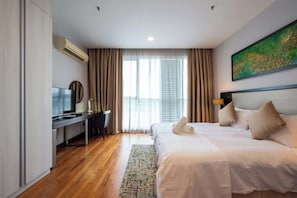 A hotel room with a bed, a desk, a TV, and a large window with curtains. - Cozy 3BR Somerset, Puteri Harbour, Legoland (Iskandar Puteri)