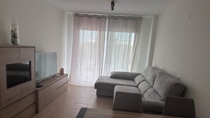 A living room with a flat-screen TV, a sofa, and a wooden cabinet.