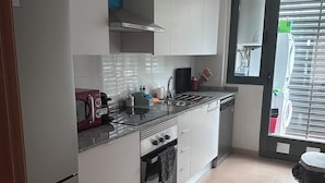 A modern kitchen with white cabinets, a stainless steel sink, and a built-in oven.