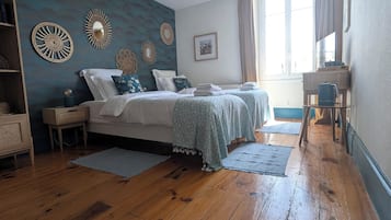 A bedroom with a bed, bedside tables, a dresser, a window with curtains, and a ceiling fan.