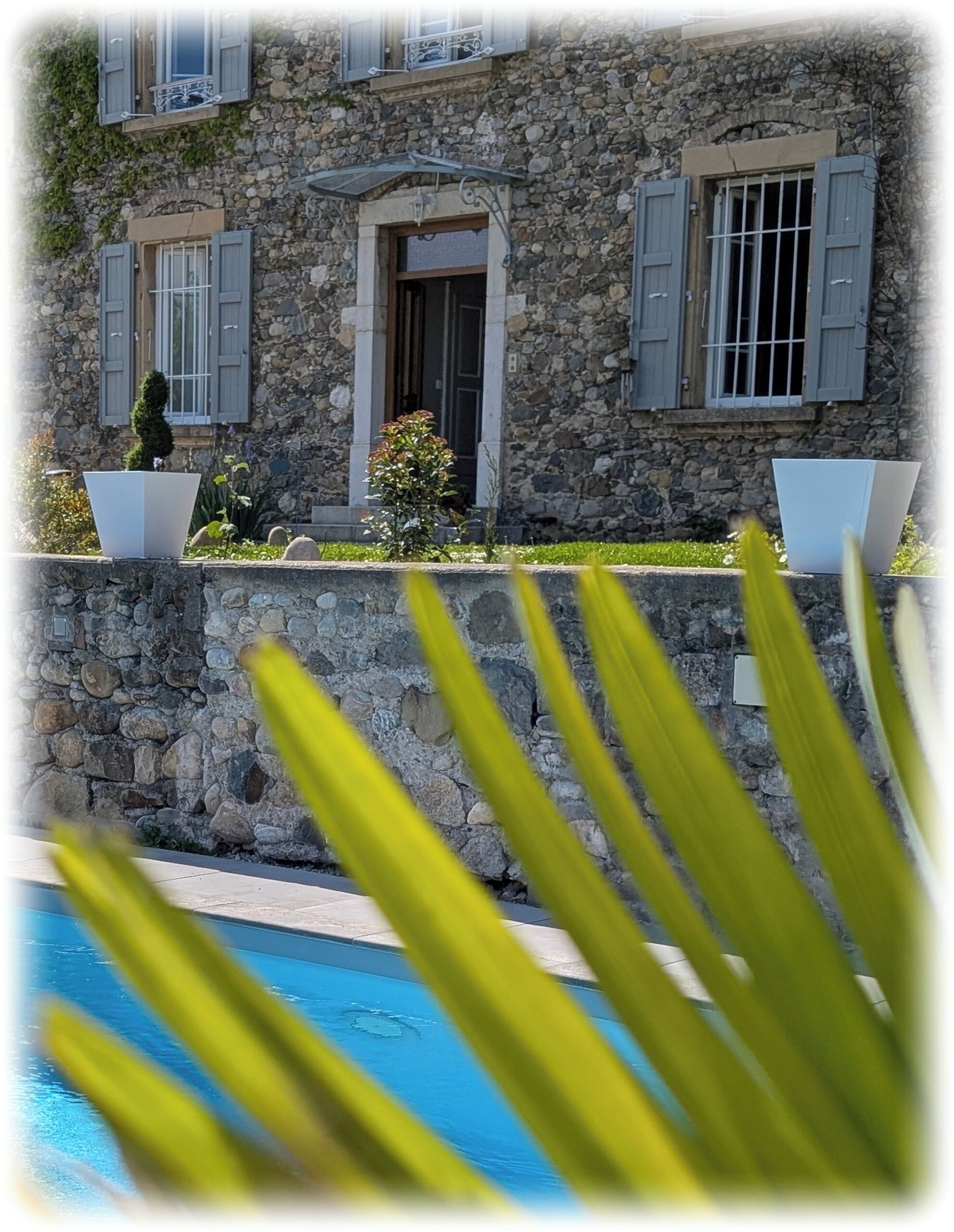 Un edificio in pietra con persiane, una piscina e vista sulla piscina.