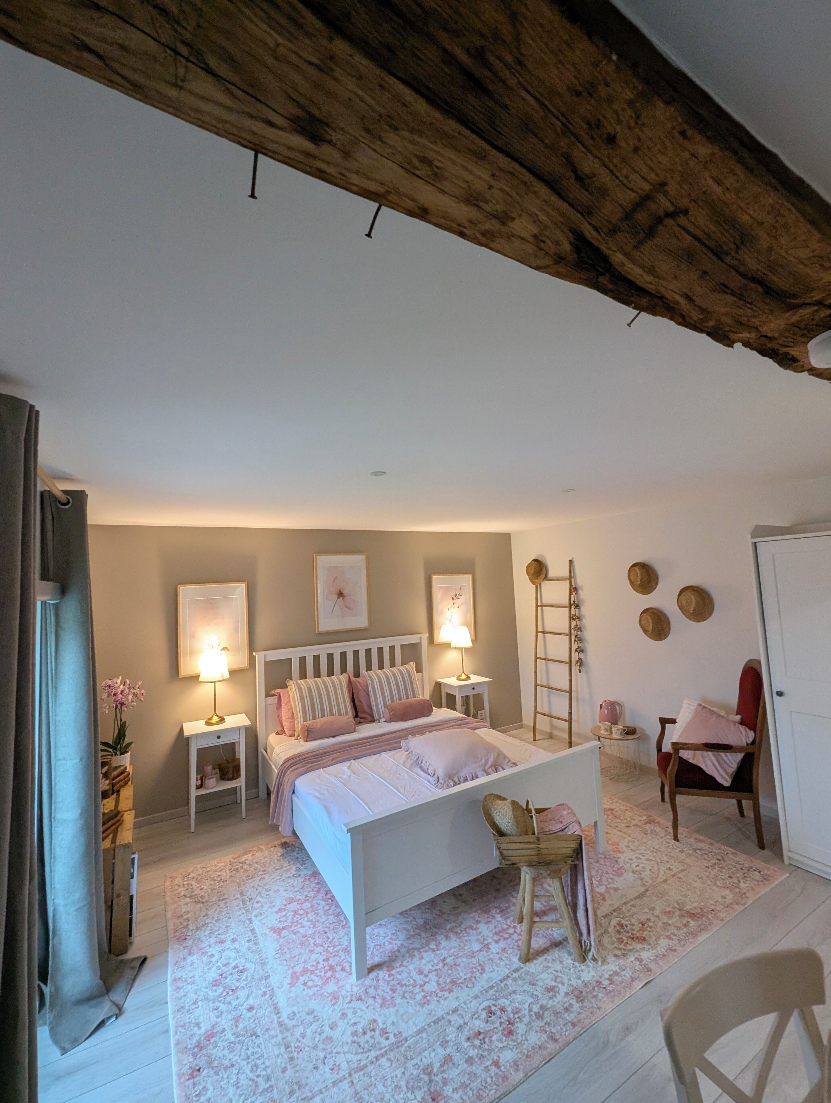 A bedroom with a bed, bedside tables, a chair, a ladder, and a door.