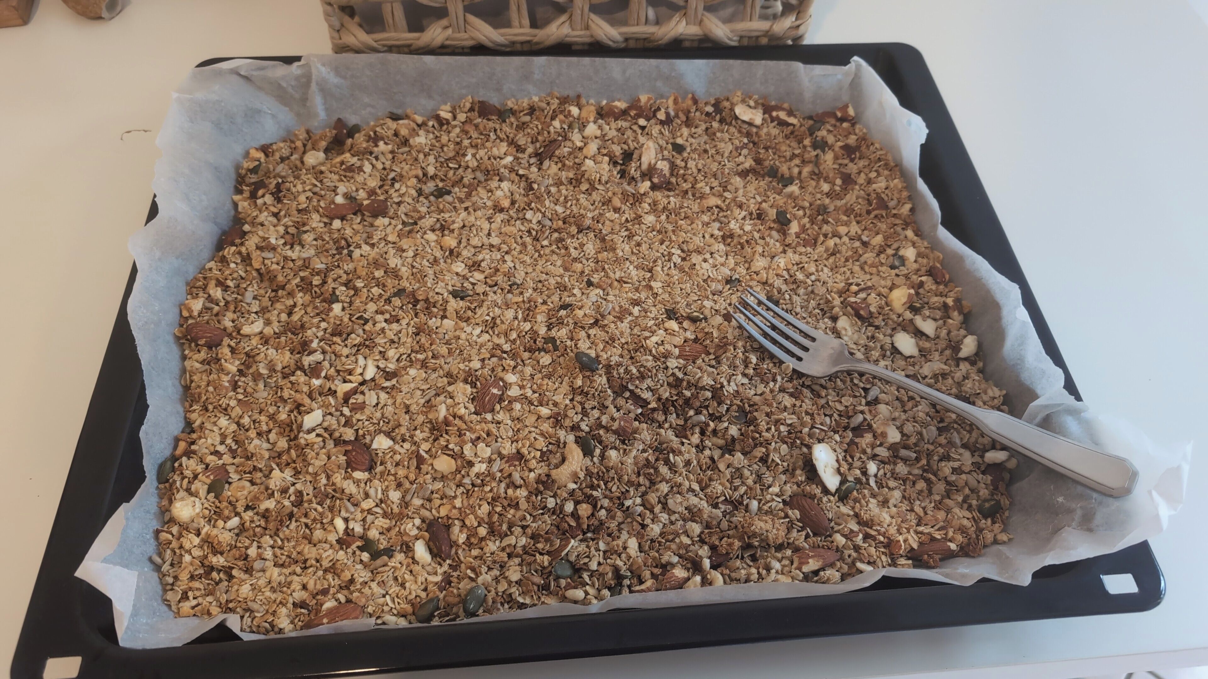 Un vassoio con granola e una forchetta sopra, poggiato su una teglia.