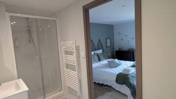 Une salle de bain moderne avec une douche à parois de verre, un lavabo blanc et un porte-serviettes.