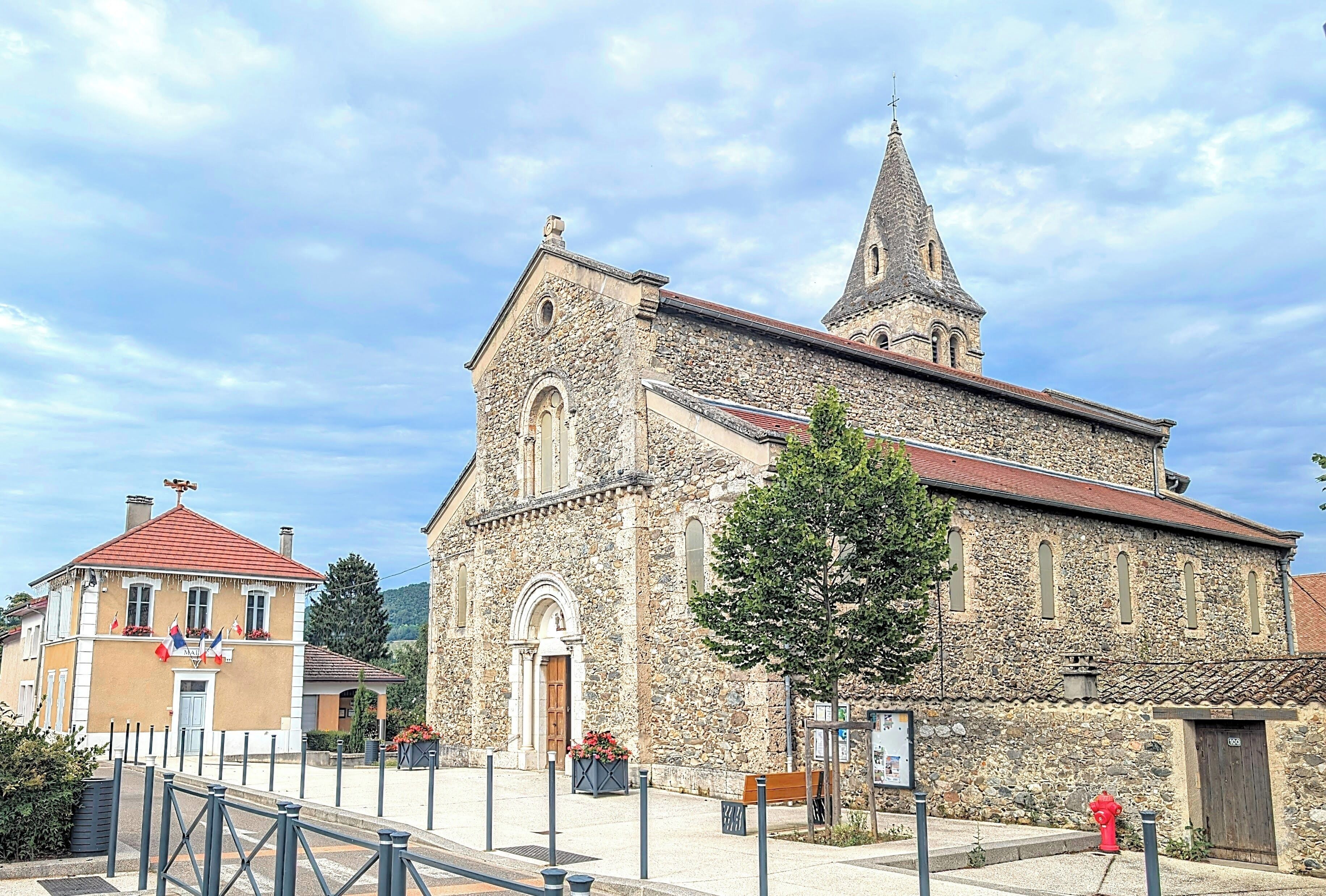 A stone church with a bell tower and a smaller building with a red roof.
