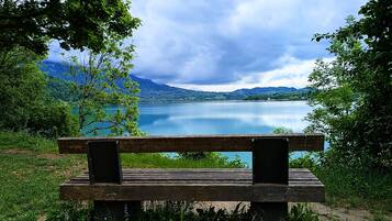 Un banco de madera con vista a un lago tranquilo y montañas al fondo.