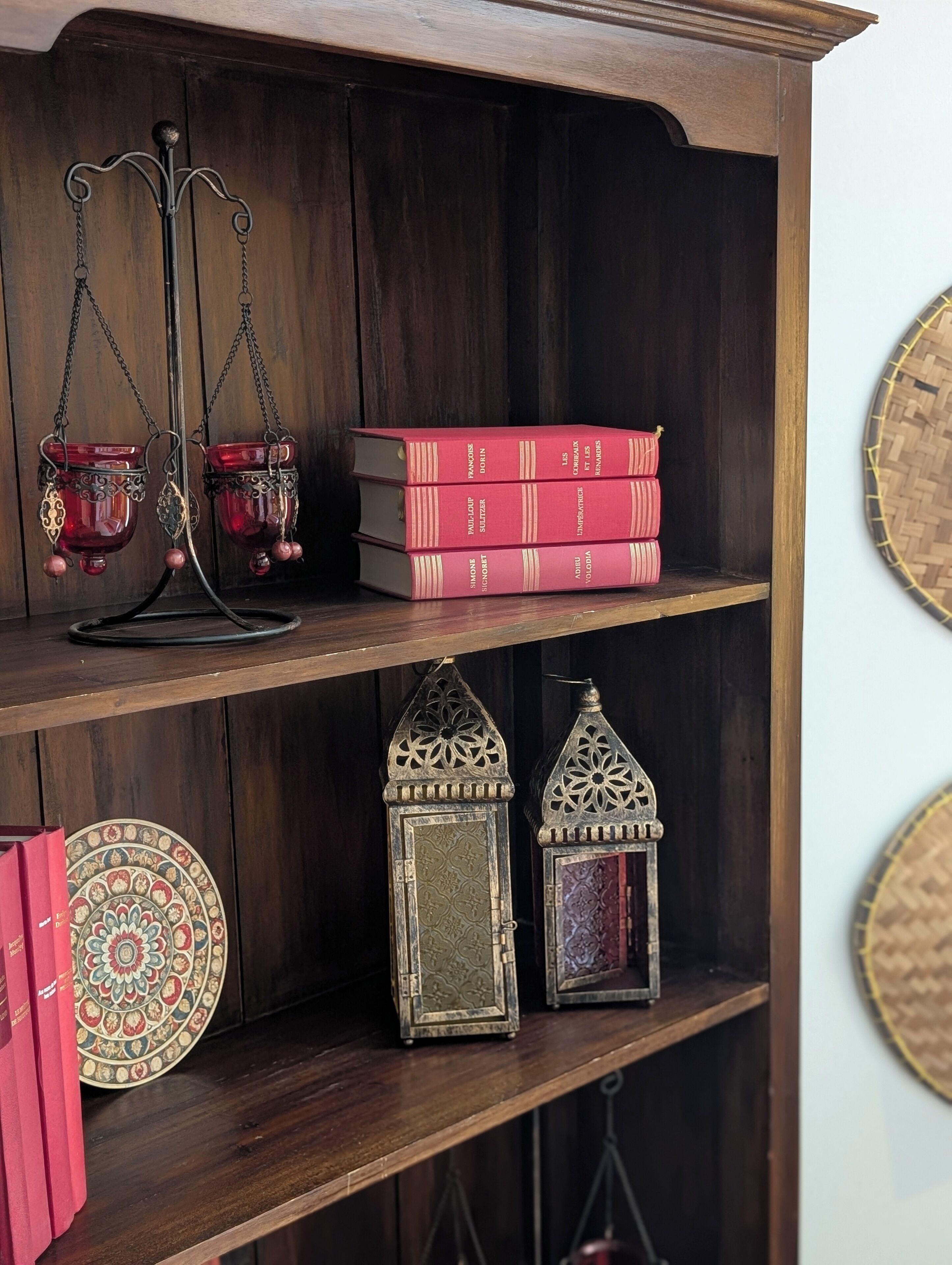 A wooden bookshelf with decorative items including books, a metal candle holder, and two lanterns.