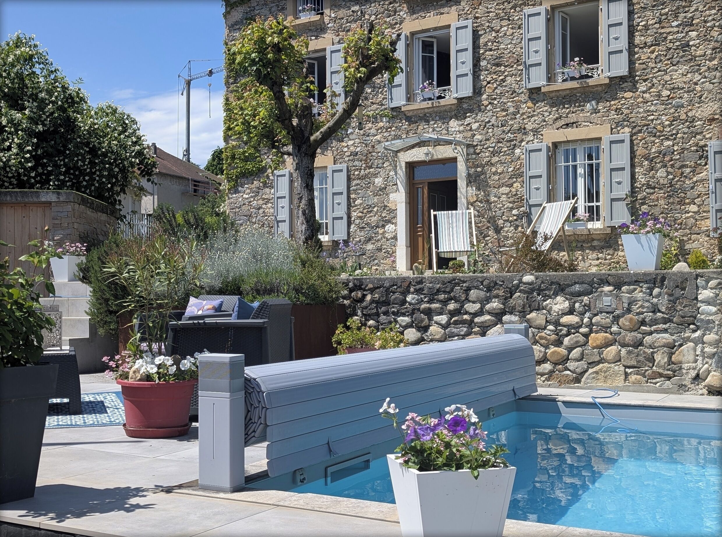 Un edificio de piedra con piscina, mobiliario exterior y jardín.
