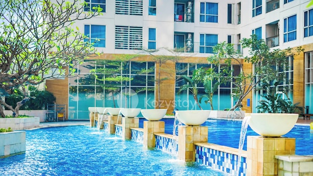 A swimming pool with multiple water features, surrounded by a building with large windows and balconies.