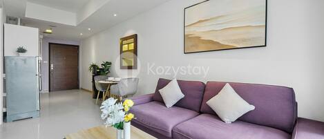 Un salón moderno con un sofá morado, una mesa de centro con flores y un cuadro en la pared.