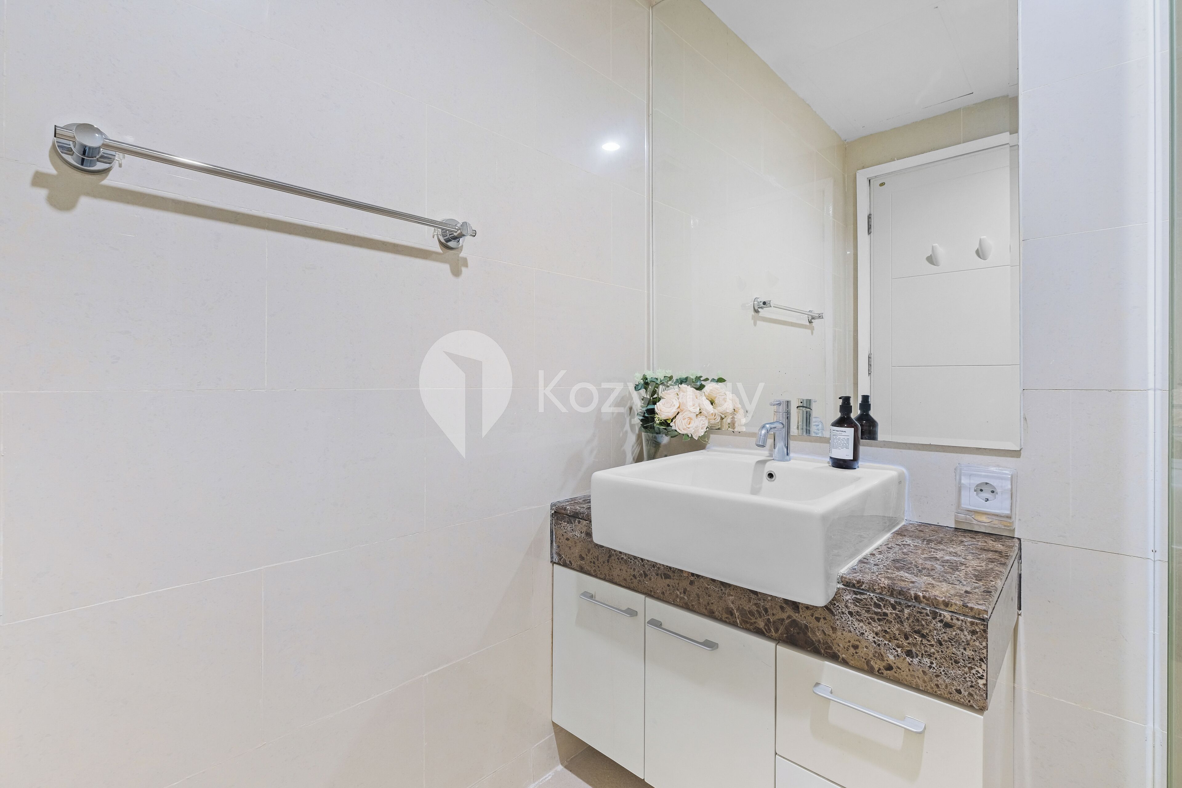 A bathroom with a white sink, granite countertop, and a mirror above it.