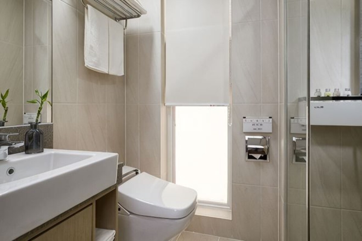 Une salle de bain moderne avec un lavabo, des toilettes et une zone de douche, le tout de couleur blanche.