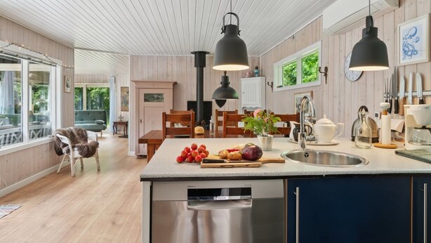 Une cuisine moderne équipée d’un lave-vaisselle Bosch, de meubles en bois et de luminaires suspendus.