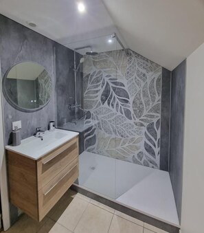Une salle de bain moderne avec un meuble-lavabo, une douche et un grand miroir.