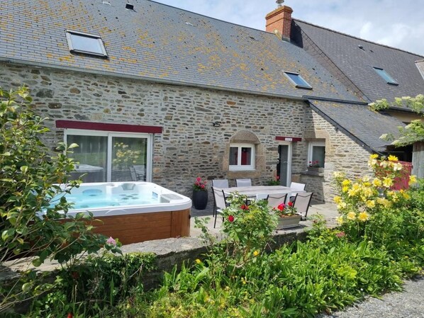 Un bâtiment en pierre doté d’un jacuzzi, d’un espace salon extérieur et d’un jardin.