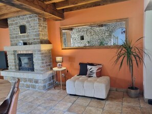 Un salon chaleureux avec une cheminée en pierre, un banc rembourré, une petite table ronde et une plante en pot.