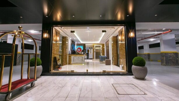 A hotel entrance with a reception desk, a digital sign, and a gold cart. - Golden new Alsalamah (Jeddah)