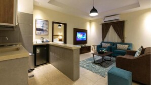 A compact living space with a kitchenette, a television, a sofa, and a coffee table. - Golden new Alsalamah (Jeddah)