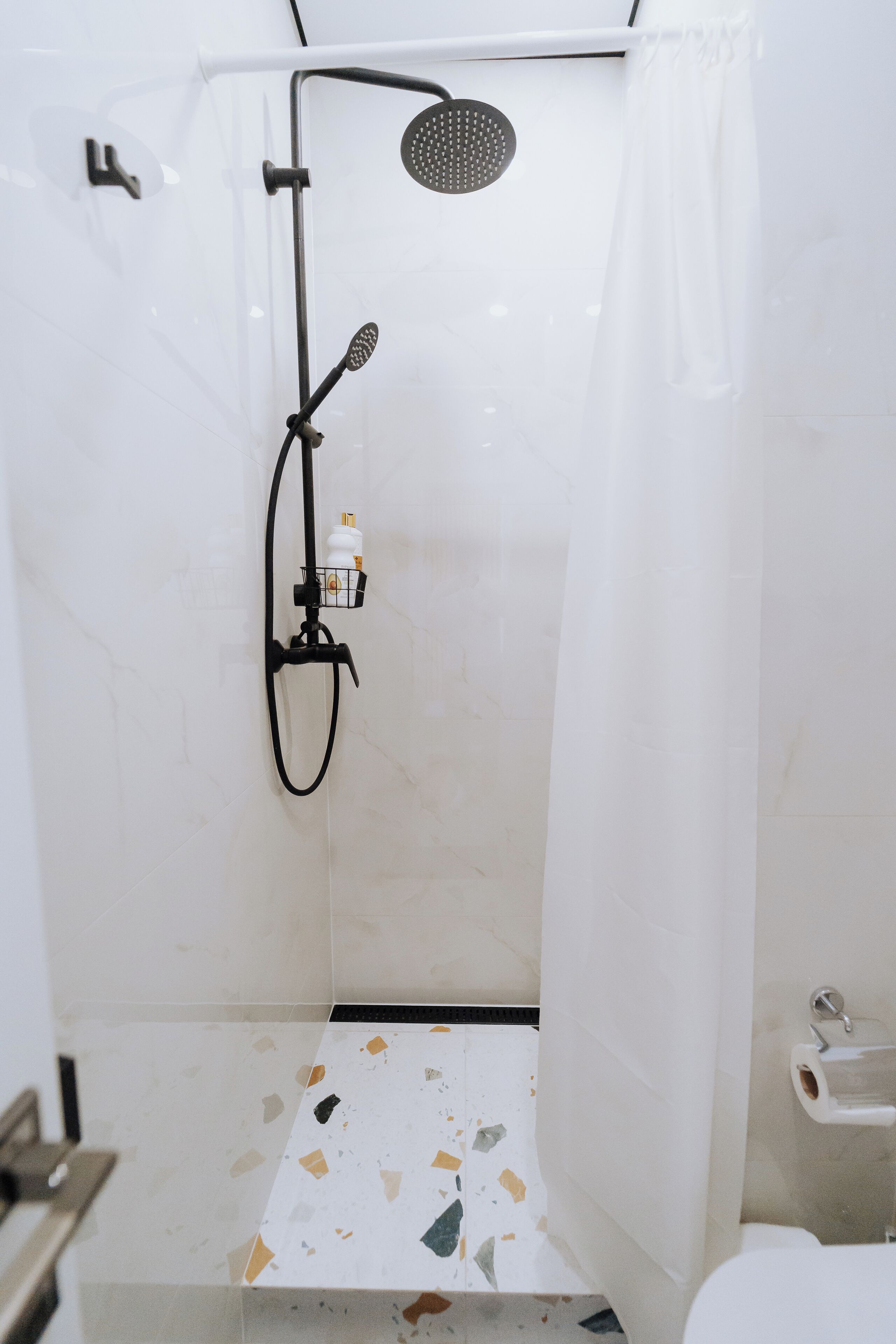 A shower with a handheld showerhead, a wall-mounted faucet, and a shower curtain.