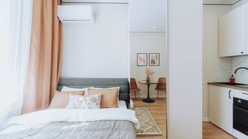 Un dormitorio moderno con cama, escritorio y kitchenette.