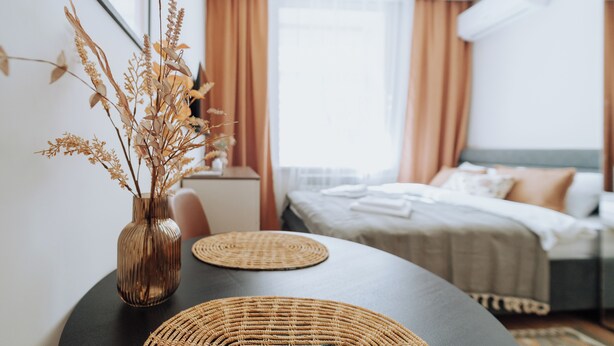 A modern hotel room with a bed, bedside table, and a vase with dried flowers. - Charming Studio by Park - Historic Center (Chișinău)