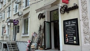 A building with multiple storefronts, including a visible sign for 'Julius Meinl' and a menu board for 'Amami' offering summer drinks. - Charming Studio by Park - Historic Center (Chișinău)