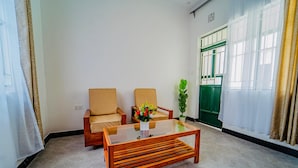 Une pièce avec deux fauteuils beiges, une table basse en bois et une porte verte.