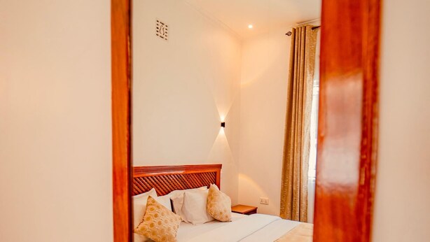 Une chambre d’hôtel avec un lit, une table de chevet, une lampe et un miroir.