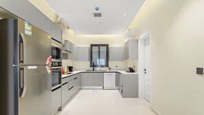 A modern kitchen with stainless steel appliances, grey cabinetry, and a white tiled floor. - Silkhaus Osus 7 (Riyadh)