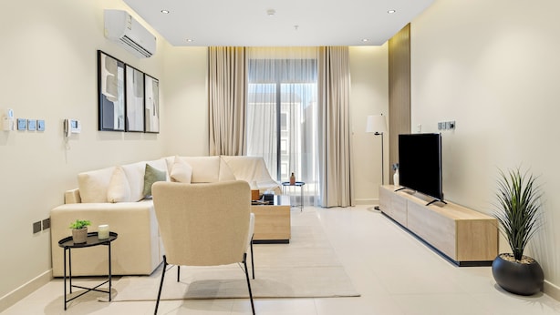 A modern living room with a sofa, a chair, a TV, and a plant. - Silkhaus Osus 7 (Riyadh)