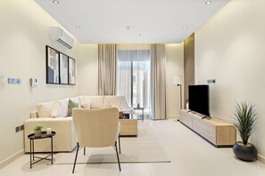 Un salon moderne avec un canapé, un fauteuil, un téléviseur et une plante.