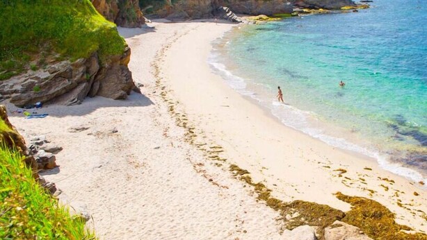 A beach with clear turquoise water, sandy shore, and green hills in the background. - LUXURY - Villa, swimming pool, jacuzzi, billiards by Groom* - by Groom (Erdeven)