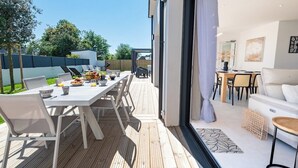 A modern outdoor dining area with a wooden deck, white furniture, and a view of the backyard. - LUXURY - Villa, swimming pool, jacuzzi, billiards by Groom* - by Groom (Erdeven)
