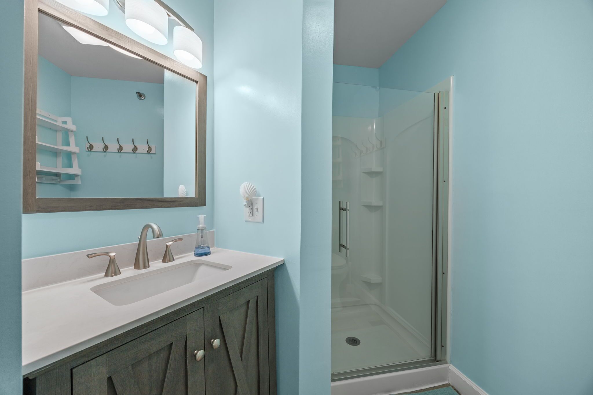 A bathroom with a large mirror, a double sink vanity, and a glass-enclosed shower.
