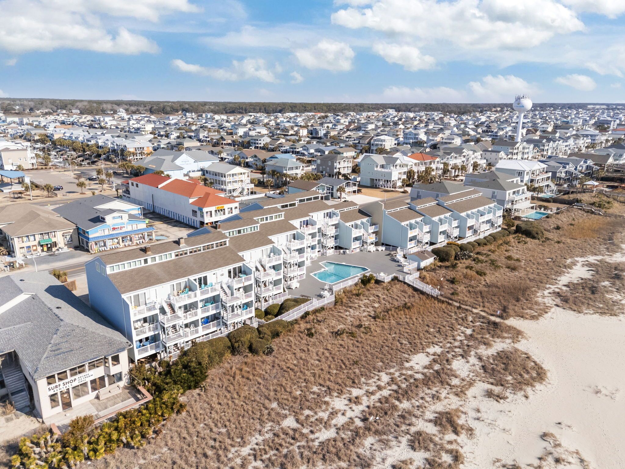 A coastal residential area with beachfront properties, including a hotel with multiple balconies and a pool.