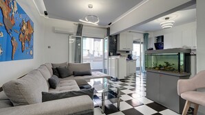 A modern living room with a checkered floor, a glass coffee table, a sofa, a fish tank, and a world map on the wall. - Aphrodite's House Upon White Tower (Thessaloniki)