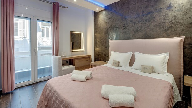 A modern hotel room with a large bed, a desk, and a sliding glass door to the balcony. - Aphrodite's House Upon White Tower (Thessaloniki)
