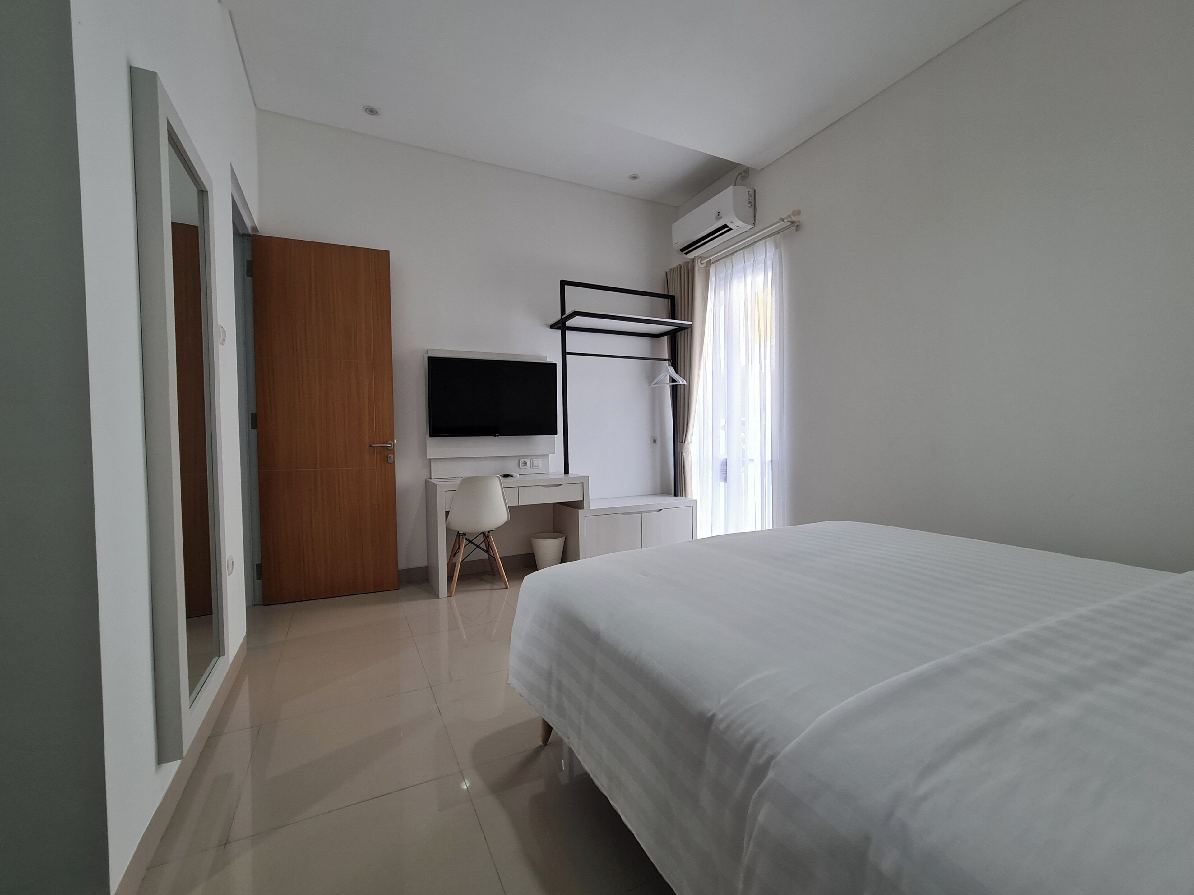 Ein modernes Hotelzimmer mit Bett, Schreibtisch mit Stuhl, Fernseher und Kleiderschrank.