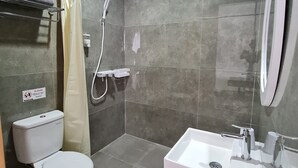 A modern bathroom with a toilet, shower, and sink. - Roemah Audy (Pogung Lor)