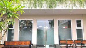 A reception area with a bench and chairs, a glass door with a push bar, and a sign indicating CCTV surveillance. - Roemah Audy (Pogung Lor)