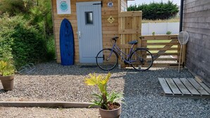 A small wooden building with a blue door, a bicycle parked in front, and a satellite dish on the right.