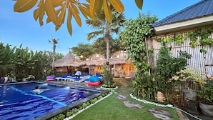 A pool area with lounge chairs and a thatched-roof structure.