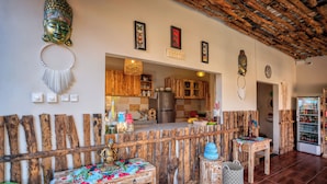 A rustic interior with a wooden bench, a small table, and a refrigerator.