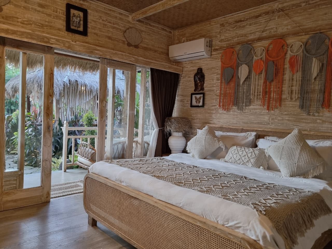 Ein Zimmer mit einem großen Bett, Holzbalkendecke und Blick ins Freie.