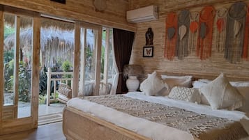 Ein Zimmer mit einem großen Bett, Holzbalkendecke und Blick ins Freie.