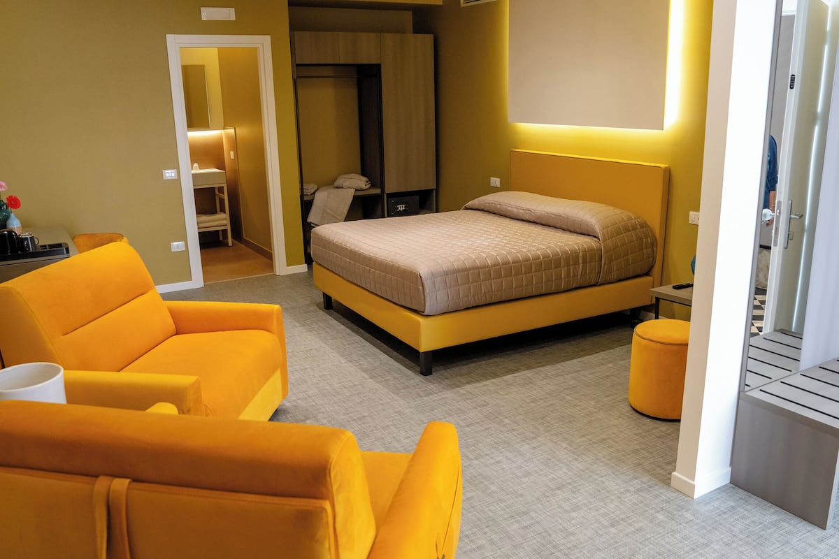 Ein Hotelzimmer mit Bett, einer Couch, einem Schreibtisch und einem Stuhl.