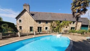 A stone building with a swimming pool in front.