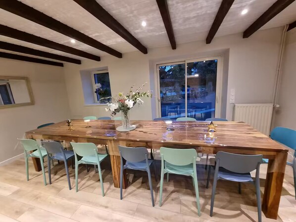 Un comedor con una gran mesa de madera, sillas azul claro y un jarrón de flores.