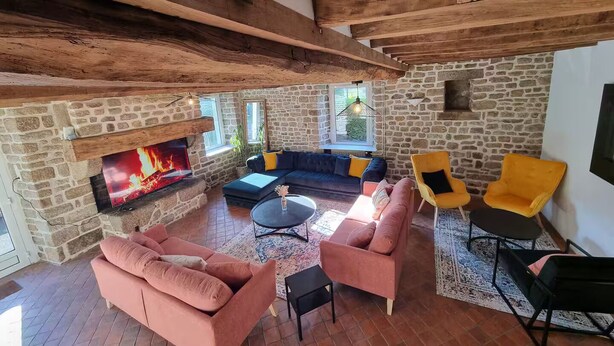 A cozy living room with a stone fireplace, a blue sofa, and pink armchairs.