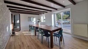 A modern dining area with a wooden table and chairs, a large window, and a view of the outdoors.
